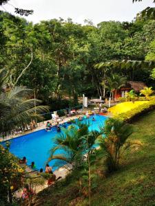 a large swimming pool with people sitting around it at Hostal Oasis The Traveler in Lanquín