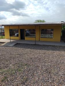 a yellow building with barred windows in a gravel yard at Casa Vacacional Quinta Sofia in Girardot