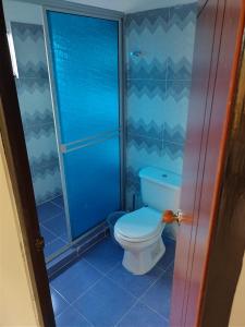 y baño azul con aseo y ducha. en Casa Vacacional Quinta Sofia en Girardot