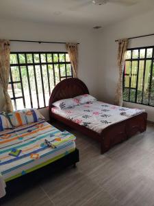 two beds in a room with windows and a bedskirts at Casa Vacacional Quinta Sofia in Girardot