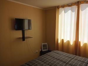 1 dormitorio con 1 cama y TV en la pared en Departamento Amoblado a Pasos del Faro, en La Serena