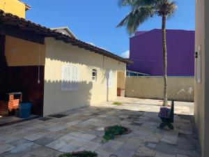 un bâtiment avec un palmier à côté d'une cour dans l'établissement Casa da Praia das Dunas, à Cabo Frio