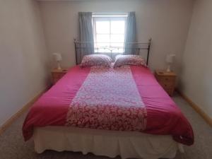 a bedroom with a pink bed with a window at The Barn in Long Sutton