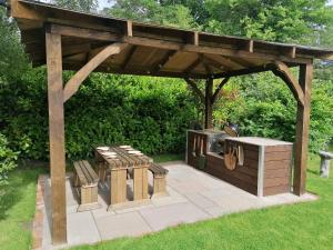 a wooden gazebo with benches and a grill at The Barn in Long Sutton