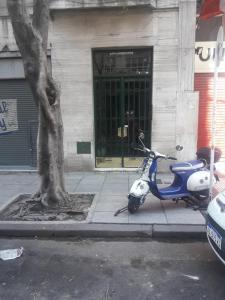 uma scooter azul e branca estacionada ao lado de uma árvore em TANGO GUAPO APART em Buenos Aires