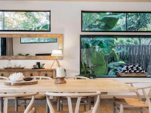 a dining room with a large wooden table and chairs at Tallowood - luxury beach house with pool & studio in Suffolk Park