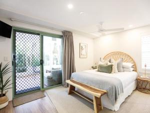 1 dormitorio con 1 cama y puerta corredera de cristal en Karinya, en Byron Bay
