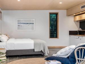 a white bedroom with a bed and a window at Tallowood - luxury beach house with pool & studio in Suffolk Park