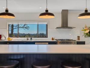 a kitchen with a counter with stools in it at Pauls Farmhouse in Newrybar