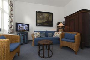ヴィーク・アウフ・フェールにあるHaus Poggfred Whg 03 Harckenのリビングルーム(青いソファ、椅子付)