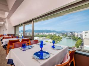 a restaurant with tables and chairs and a large window at HOTEL MYSTAYS Hiroshima Peace Park in Hiroshima