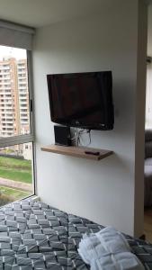 a flat screen tv on a wall in a bedroom at Apartaestudio Sector Hayuelos in Bogotá