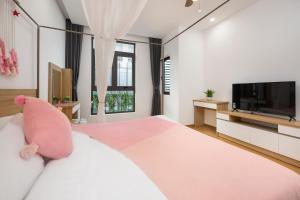 a bedroom with a white bed and a tv at Arrive Hotel & Apartment in Danang