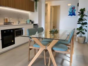 a dining room with a glass table and chairs at Mariner's Cove ~ Luxe Waterfront Apartment in Mindarie