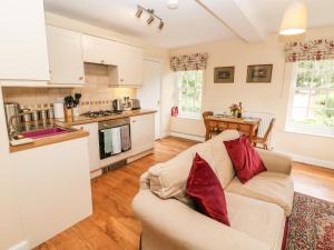 a living room with a couch and a kitchen at Underbank Hall Cottage in Stocksbridge