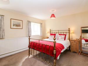 a bedroom with a bed with a red blanket at Underbank Hall Cottage in Stocksbridge