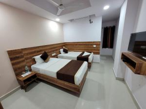a bedroom with two beds and a flat screen tv at Hotel Prime Jubilee in Hyderabad