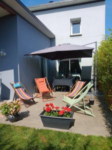 eine Terrasse mit 2 Liegestühlen und einem Sonnenschirm in der Unterkunft Gite les bambous en BAIE DU MONT ST MICHEL in Dragey