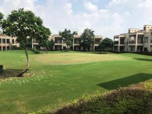 um campo de golfe com um verde e alguns edifícios em Premium Apartment in Tarudhan Valley Golf Resort em Manesar