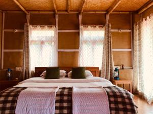 a bedroom with two beds and two windows at PaliGhar Farmstay in Kalimpong