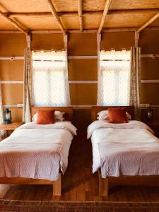 two beds in a room with two windows at PaliGhar Farmstay in Kalimpong