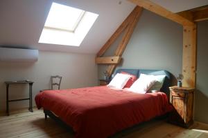 a bedroom with a large red bed with a skylight at chambre d hôte La Grange in Pommiers-en-Forez
