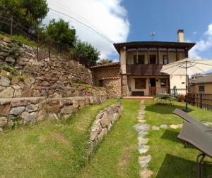 una casa con una pared de piedra junto a un patio en Casona Angliru en Riosa