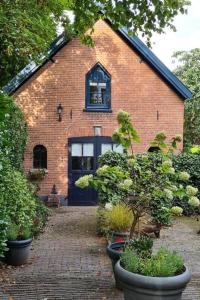 a brick building with a black door and some plants at In het koetshuis in Apeldoorn