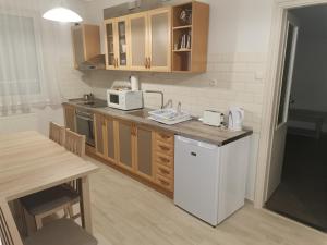 ハイドゥソボスローにあるZoli Apartmanok-Balcony Kölcsey 32のキッチン(木製キャビネット、白い冷蔵庫付)