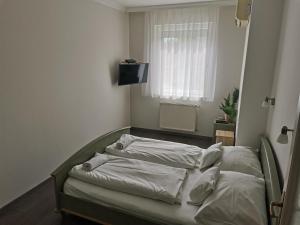 a bed with white sheets and a television in a room at Zoli Apartmanok-Balcony Kölcsey 32 in Hajdúszoboszló