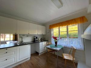 a kitchen with white cabinets and a table with flowers on it at Olastugu in Al