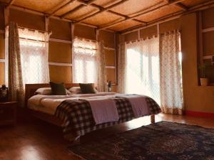 a bedroom with a bed in a room with windows at PaliGhar Farmstay in Kalimpong