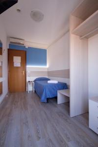 una camera con letto blu e pavimento in legno di Hotel Serenella a Lido di Jesolo