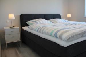 a black bed with a striped blanket and a night stand at Meerblick Fehmarnsund 1 - direkt am Strand in Fehmarnsund