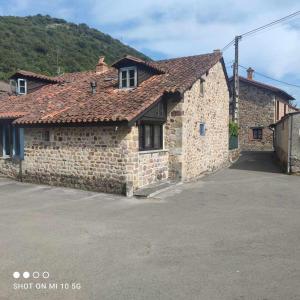 Casa Rural El Amparuco في Treceño: مبنى حجري امامه موقف سيارات