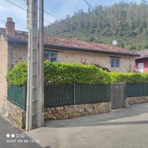 una casa con una valla de piedra y una puerta en Casa Rural El Amparuco, en Treceño