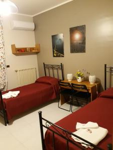 a room with two beds and a table and a tableablish at La casa di Bia in Corleone