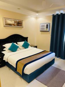 1 dormitorio con 1 cama grande con almohadas azules en بنان للشقق المفروشة, en Tabuk