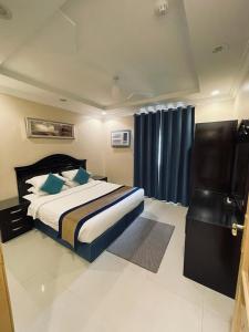1 dormitorio con 1 cama grande y cortinas azules en بنان للشقق المفروشة, en Tabuk