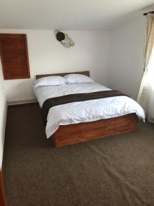 ein Schlafzimmer mit einem Bett mit weißen Laken und Kissen in der Unterkunft La Butuci in Târgu Ocna