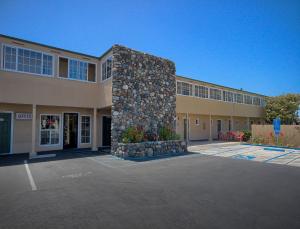 a building with a stone wall in a parking lot at Sea Breeze Inn - San Simeon in San Simeon