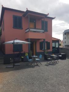 a pink house with tables and chairs and an umbrella at FX Carvalhal in Funchal