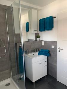 a bathroom with a sink and a shower with blue towels at Ferienwohnung Familie Heite in Olpe