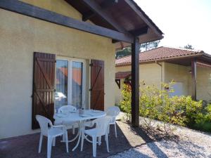 カップブルトンにあるVilla Pour 4 Personnes Avec Piscine En Copropriete- Residence Le Bosquet Aux Ecureuilsのパティオ(白いテーブル、椅子付)