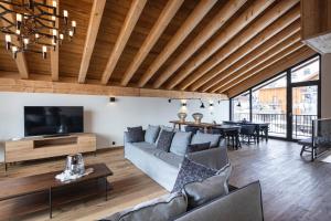 ein Wohnzimmer mit einem Sofa und einem TV in der Unterkunft Chalet le Blue Moon in L'Alpe-d'Huez