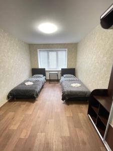 two beds in a room with a wooden floor at Апартаменты Проспект Победы 101 in Chernihiv