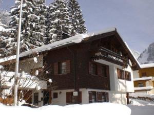 a building in the snow with a snow covered tree at Haus Maschol in Wald am Arlberg