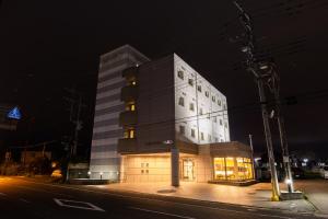 a tall white building on a city street at night at セントラルホテル高萩 in Takahagi