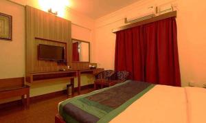 Cette chambre comprend un lit et un bureau avec une télévision. dans l'établissement FabHotel Spiro Grand, à Bangalore
