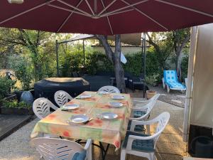 einen Tisch und Stühle mit Sonnenschirm auf einer Terrasse in der Unterkunft Mobile-home aux Cigales,Le Muy Colorado 4-6 Personnes in Le Muy